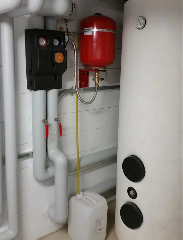 Ballon d'eau chaude solaire et vase d'expansion rouge dans un local technique