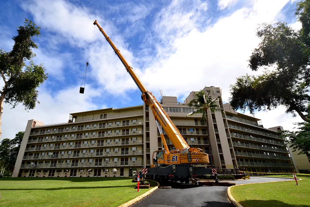 Grue hissant des capteurs solaires thermiques sur le toit d'un immeuble