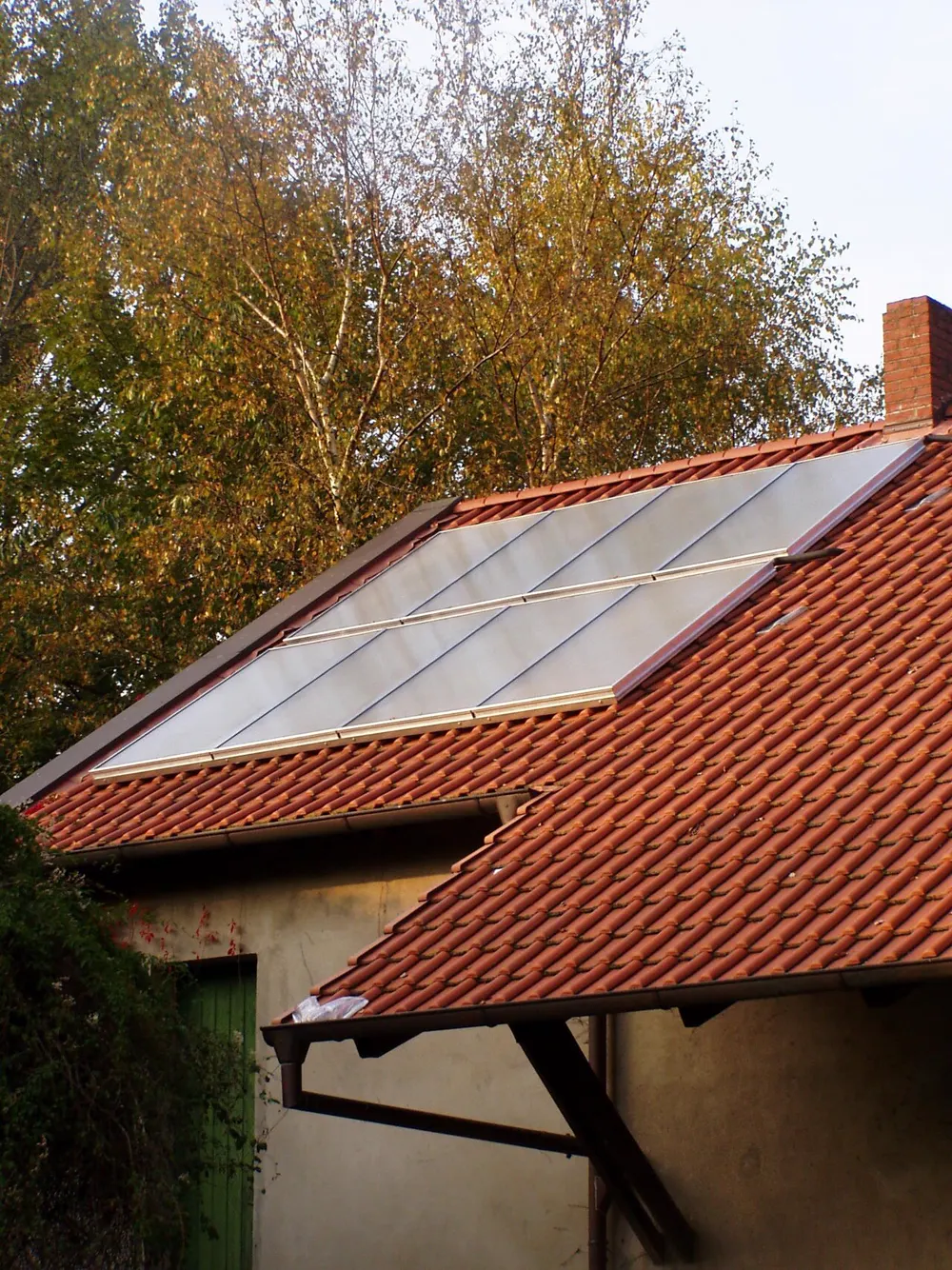 Rangée de capteurs solaires plans posés sur un toit en tuiles rouges