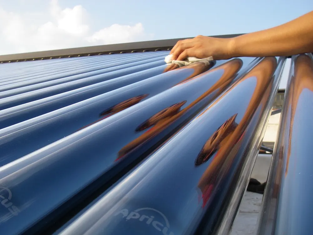 Main nettoyant les tubes d'un capteur solaire à tubes sous vide